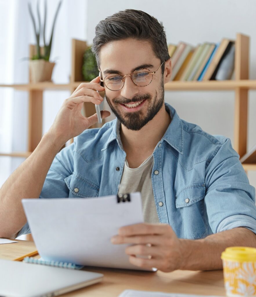 Happy young unexperienced male prepares business report, asks advice or consultancy in professional